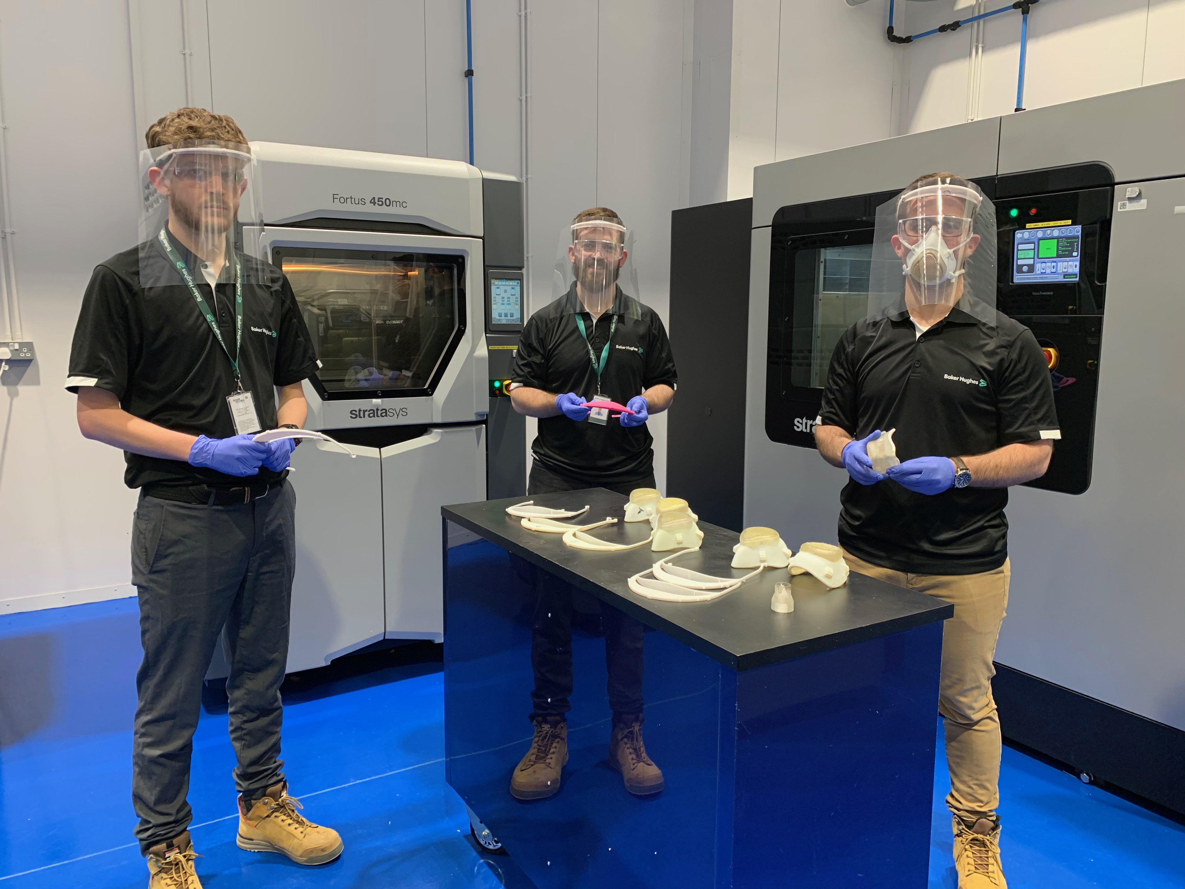 Three male Baker Hughes employee demonstrating a 3D printed medical equipment