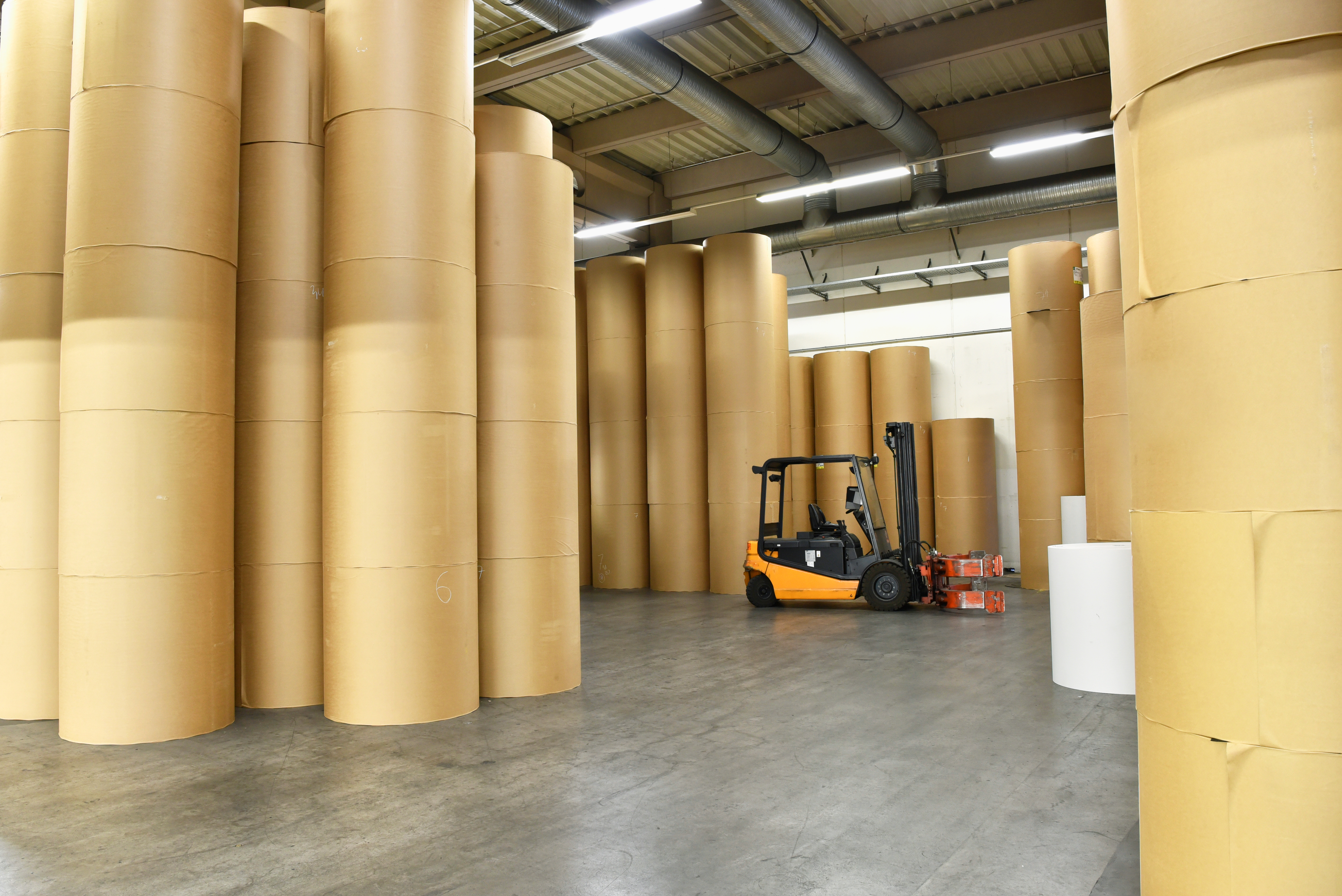 interior shot of a paper mill with stacks of paper and a forklift