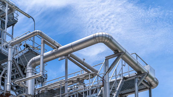 Industrial view at oil and gas refinery plant for industry zone with and cloudy sky, Steel pipeline with insulation, Equipment, cables and piping as found inside of a industrial power plant