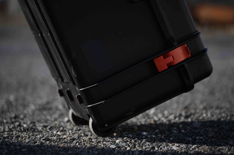 Ca-Zoom HD PTZ inspection camera inside portable transportation case being wheeled behind an inspector on a nuclear site. Close up of the transport case wheels which easily move over gravel.