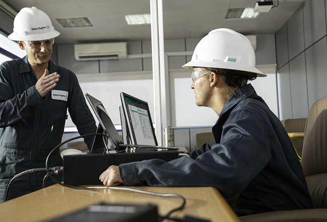 Two Baker Hughes employees in the field working.