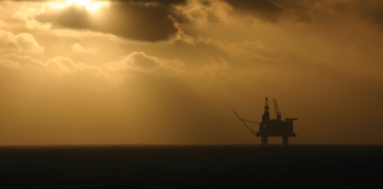 Photo of an offshore oil rig at sunset.