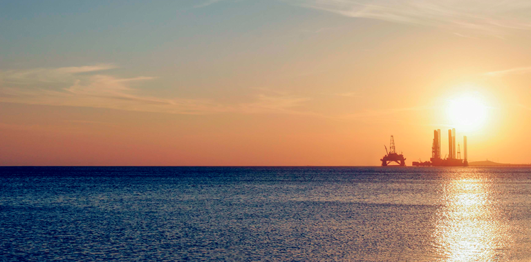 Photo of an offshore oil rig at sunset.