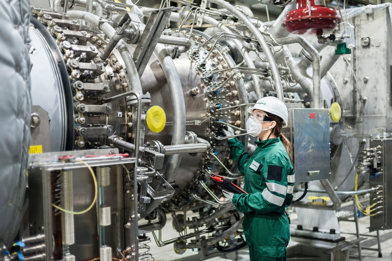 woman in PPE inspecting a hydrogen turbine