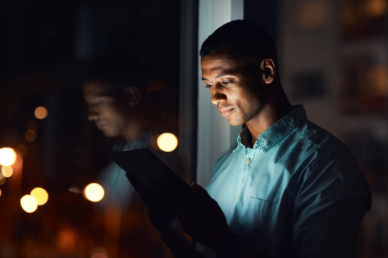 Shot of a handsome young businessman using a digital tablet while working late in his office